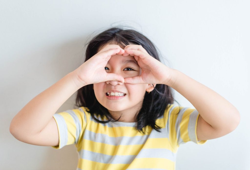 Girl making heart shaped hands.