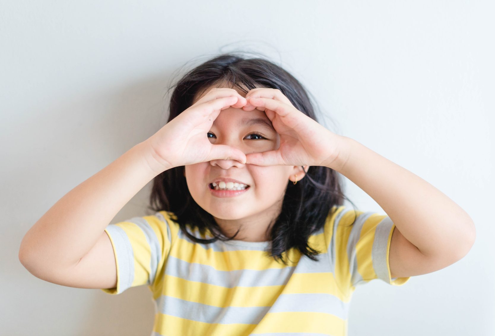 Happy kid making a heart our of hands.